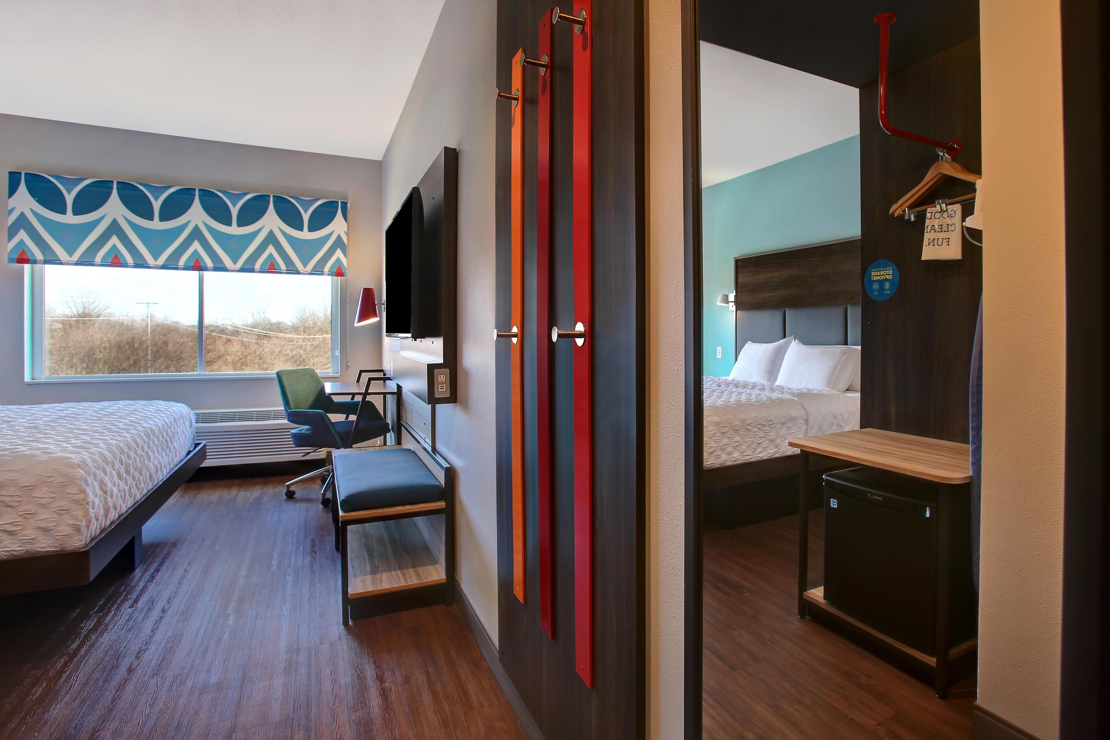 Quarto de hotel moderno com duas camas, uma escrivaninha e uma cadeira.