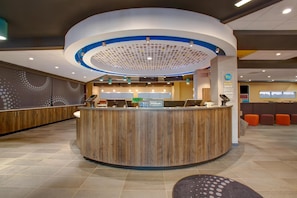 A modern hotel reception area with a curved wooden reception desk, multiple computer monitors, and a circular ceiling design. - Tru by Hilton Alcoa Knoxville Airport (Alcoa)
