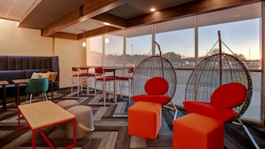 A modern interior with a sofa, chairs, a table, and a hanging chair by a large window. - Tru by Hilton Alcoa Knoxville Airport (Alcoa)
