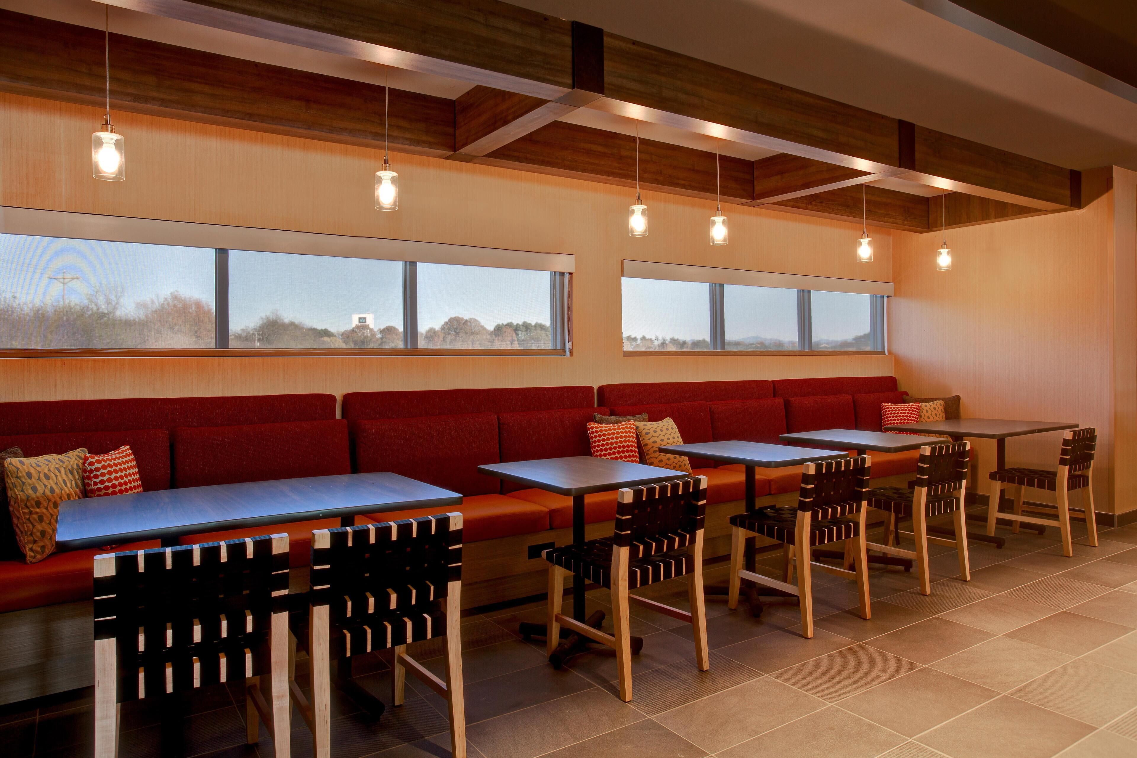 A restaurant with red booths, wooden tables, and black chairs.