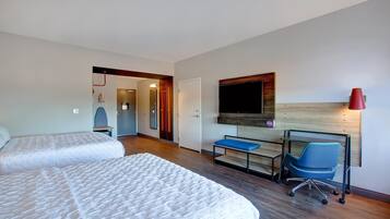 A hotel room with two beds, a desk, a chair, a TV, and a red lamp.