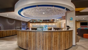 A hotel reception area with a wooden reception desk, a Hilton sign, and a circular ceiling design. - Tru by Hilton Alcoa Knoxville Airport (Alcoa)