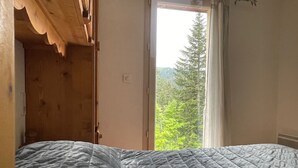 Ein Schlafzimmer mit großem Fenster, einem Bett und einem Holzschrank.