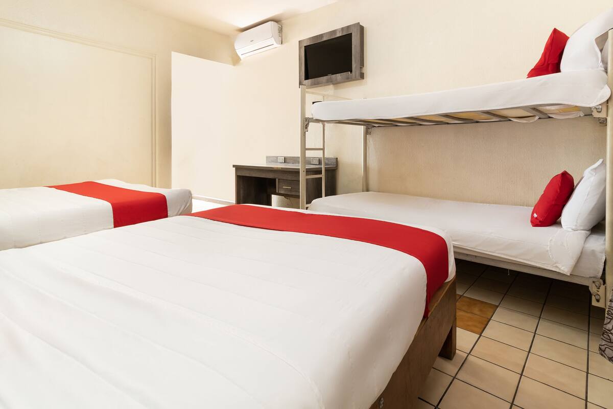 A hotel room with bunk beds, a desk, and a TV.