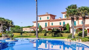 A large swimming pool with a clear blue water surface, surrounded by well-maintained greenery and palm trees. - Port Pals "Summer Vibes" by Interhome (Pals)