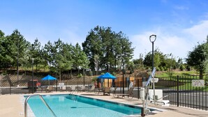 A rectangular pool with a metal ladder, surrounded by a fence, and shaded by blue umbrellas. - Staybridge Suites Atlanta Ne - Duluth by IHG (Duluth)