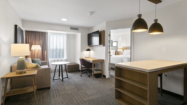 A hotel room with a sofa, desk, chair, and a bed. - Staybridge Suites Atlanta Ne - Duluth by IHG (Duluth)