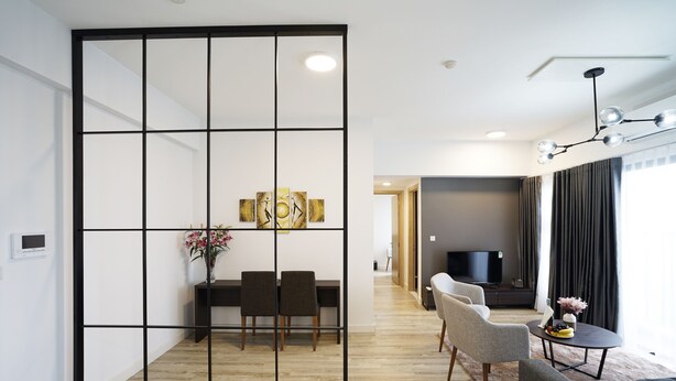 A modern living room with a dining area, a TV, and a large window with curtains. - The First Stay Hotel (Phung Cong)