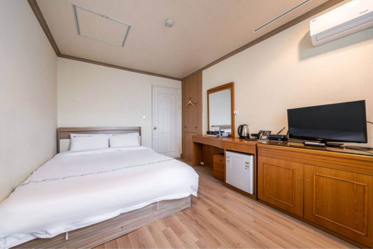 Ein Hotelzimmer mit einem Bett, einem Holzschrank, einem Fernseher und einem Spiegel.