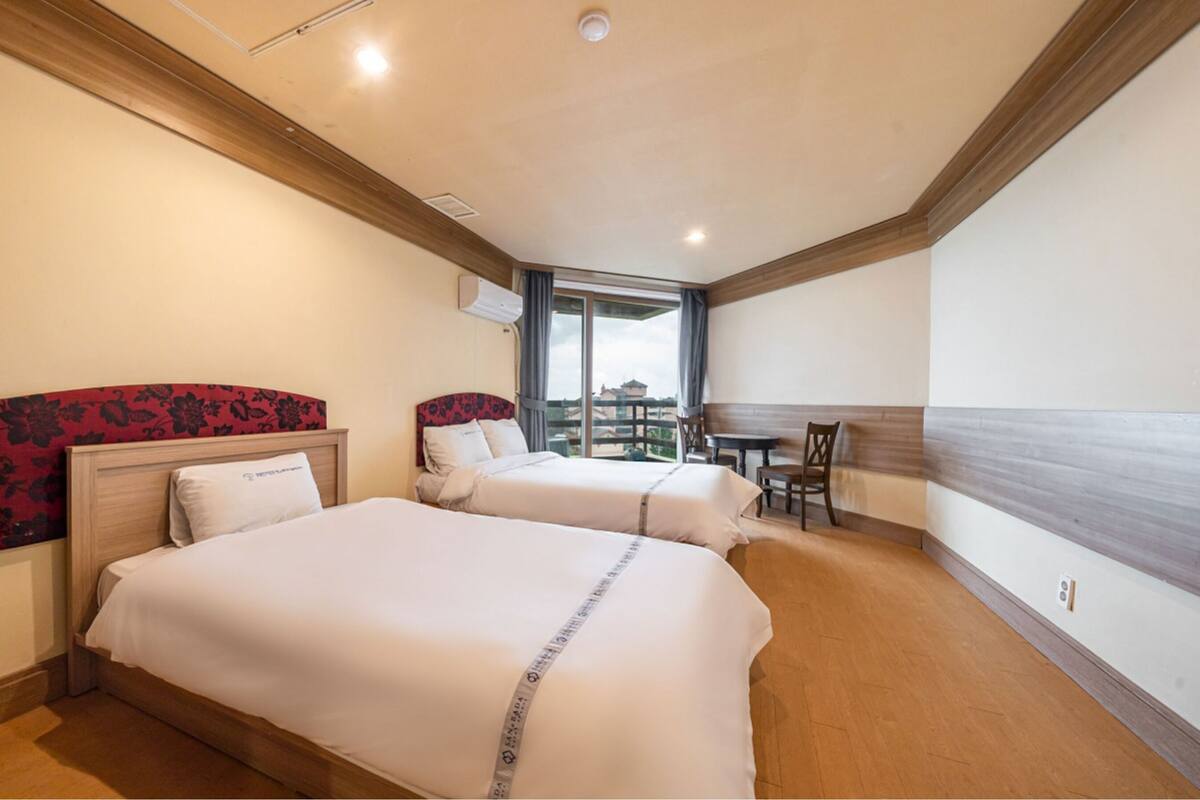Ein Hotelzimmer mit zwei Betten, einem Essbereich und einem großen Fenster mit Blick.