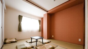 A room with tatami mat flooring, a small table, and cushions.