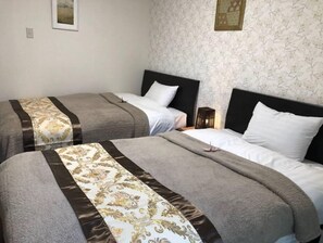 Une chambre d’hôtel avec deux lits, chacun doté d’une tête de lit, d’une table de chevet et d’une lampe fixée au mur.