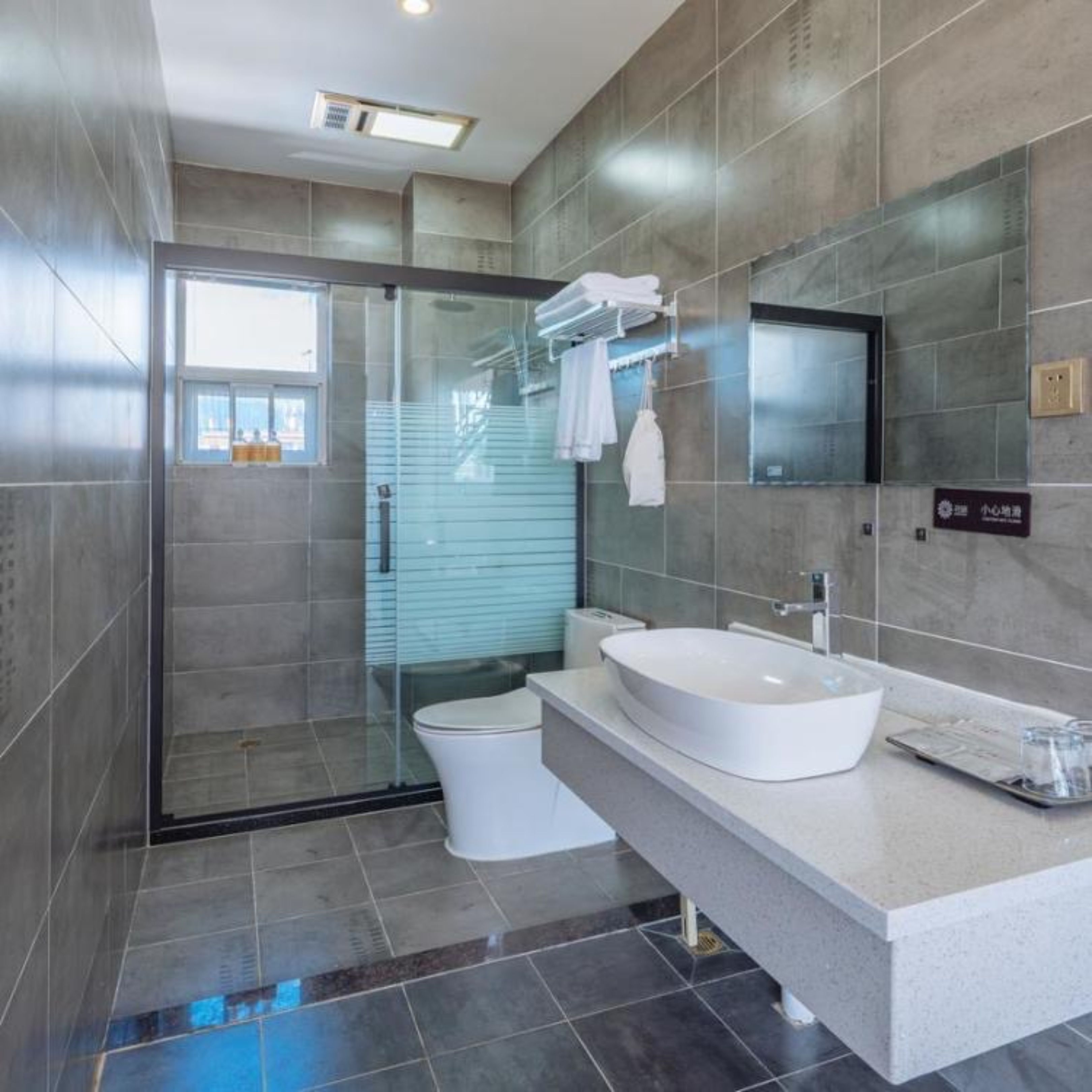 A modern bathroom with a glass shower enclosure, a white sink, and a large mirror.