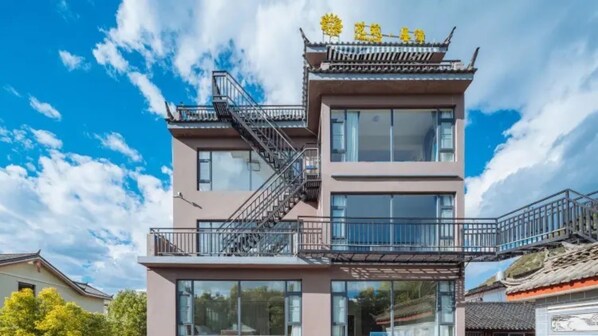 Un edificio moderno con tejado de estilo chino, una escalera y ventanas grandes.
