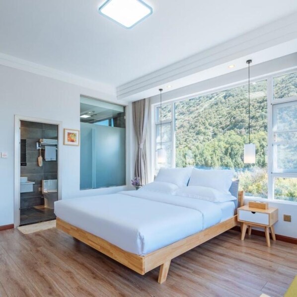 A modern bedroom with a large bed, a walk-in closet, and a view of a forest through large windows. - Floral Hotel · Mo Tan Lijiang (Lijiang)
