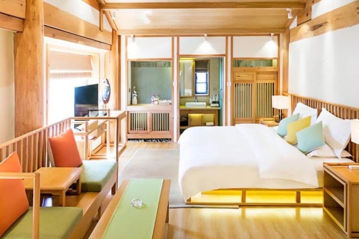 A wooden cabin-style room with a bed, a desk, and a seating area.