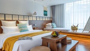 A modern hotel room with a wooden ceiling, a large bed with white bedding, a small wooden table with a fruit bowl, and a window with a view.