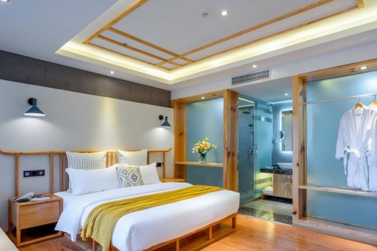 A modern bedroom with a wooden bed, bedside tables, and a glass shower enclosure.