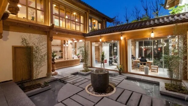A traditional building with a courtyard, wooden beams, and a stone fountain.