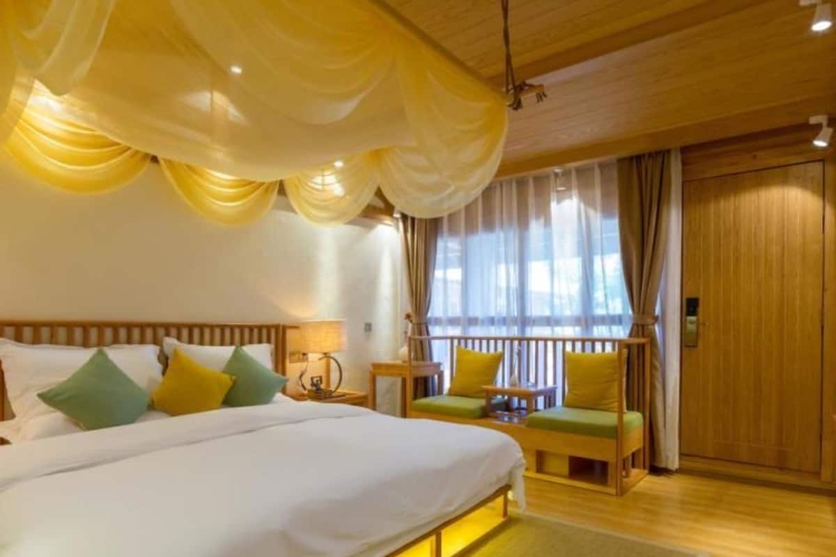 A bedroom with a large bed, bedside tables, a chair, and a window with curtains.