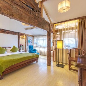 A room with a wooden bed, a blue chair, a floor lamp, and a large window with curtains.