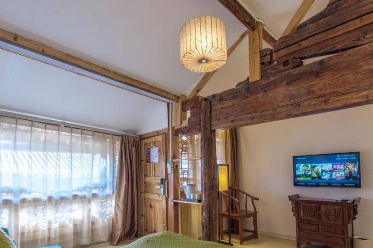 Una habitación con cama, televisión y vigas de madera en el techo.