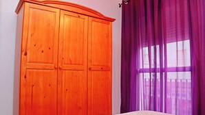 Een slaapkamer met een houten garderobe, een bed en paarse gordijnen.