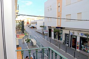 A street view with a 'Phone House' store, a 'El Oso Coloso' shop, and a pedestrian walkway with a green railing. - Oenologist apartment with WiFi (Conil de la Frontera)