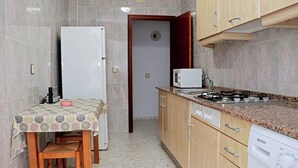 Een praktische keuken met een koelkast, magnetron, fornuis en vaatwasser.