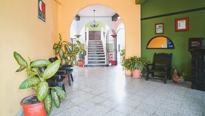 Een hotel lobby met een trap, planten in potten en een receptiebalie.