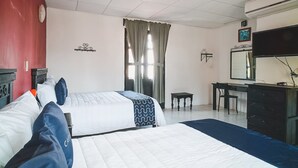 Een hotelkamer met twee bedden, een bureau, een stoel, een televisie en een airconditioning.