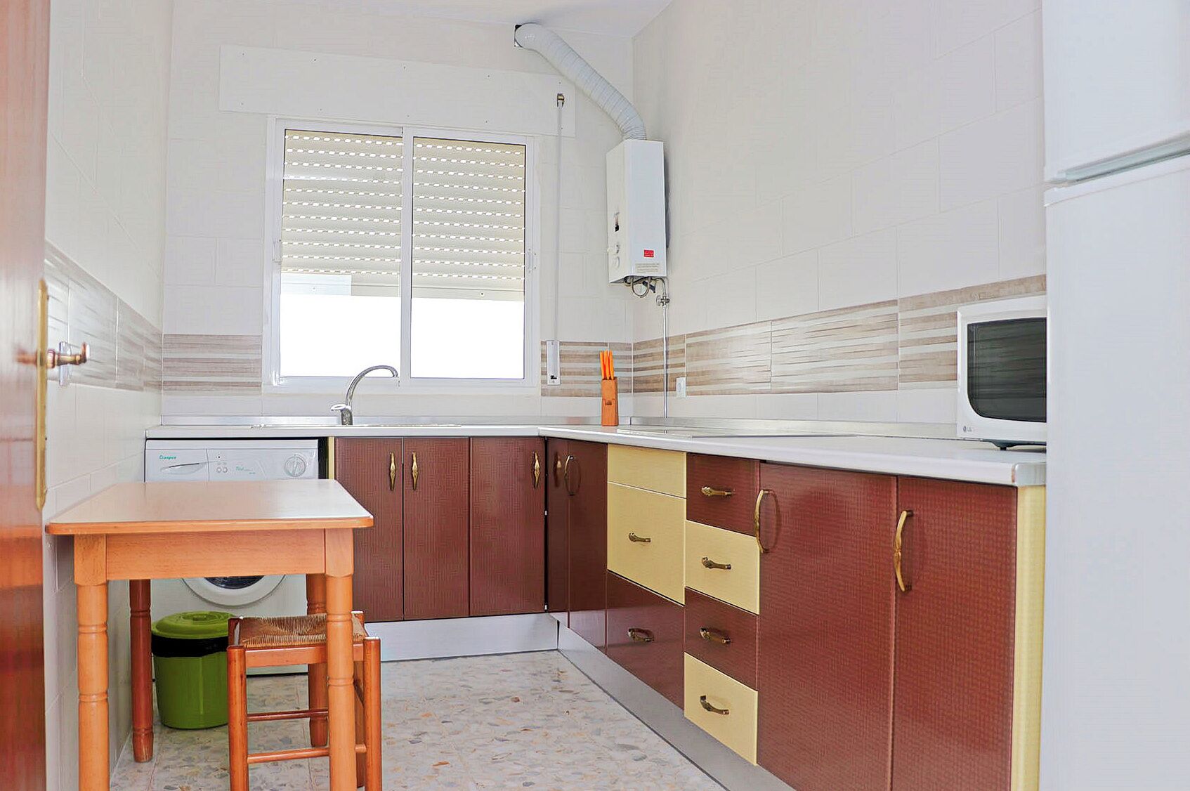 Una cocina compacta con lavadora integrada, microondas y fregadero.