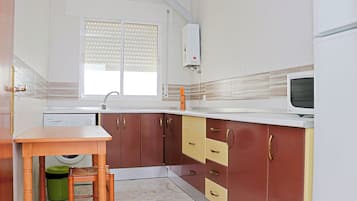 Una cocina compacta con lavadora integrada, microondas y fregadero.