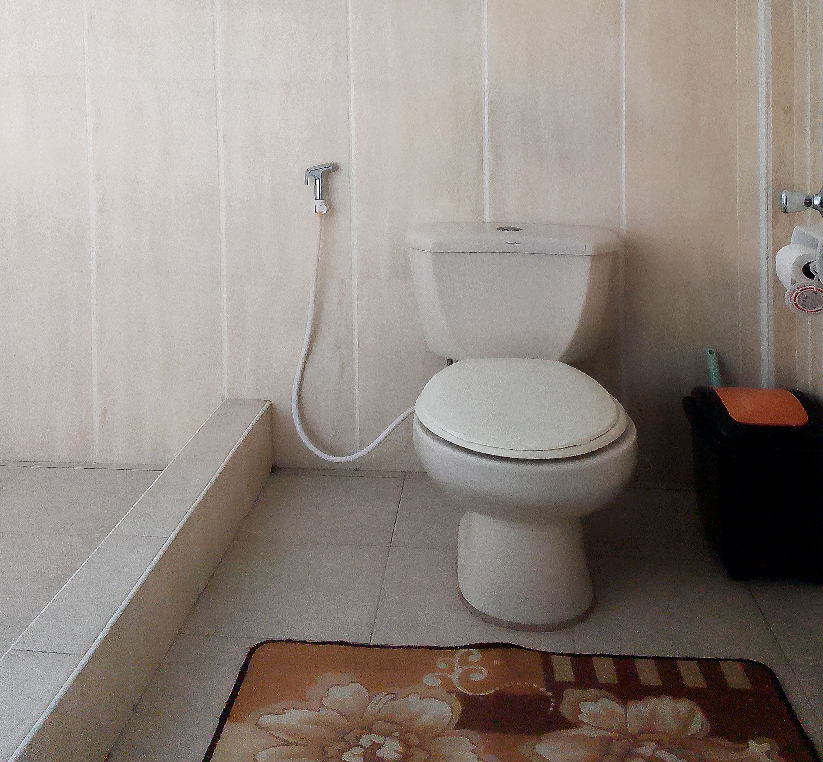 A bathroom with a toilet, a bidet, and a small trash bin.