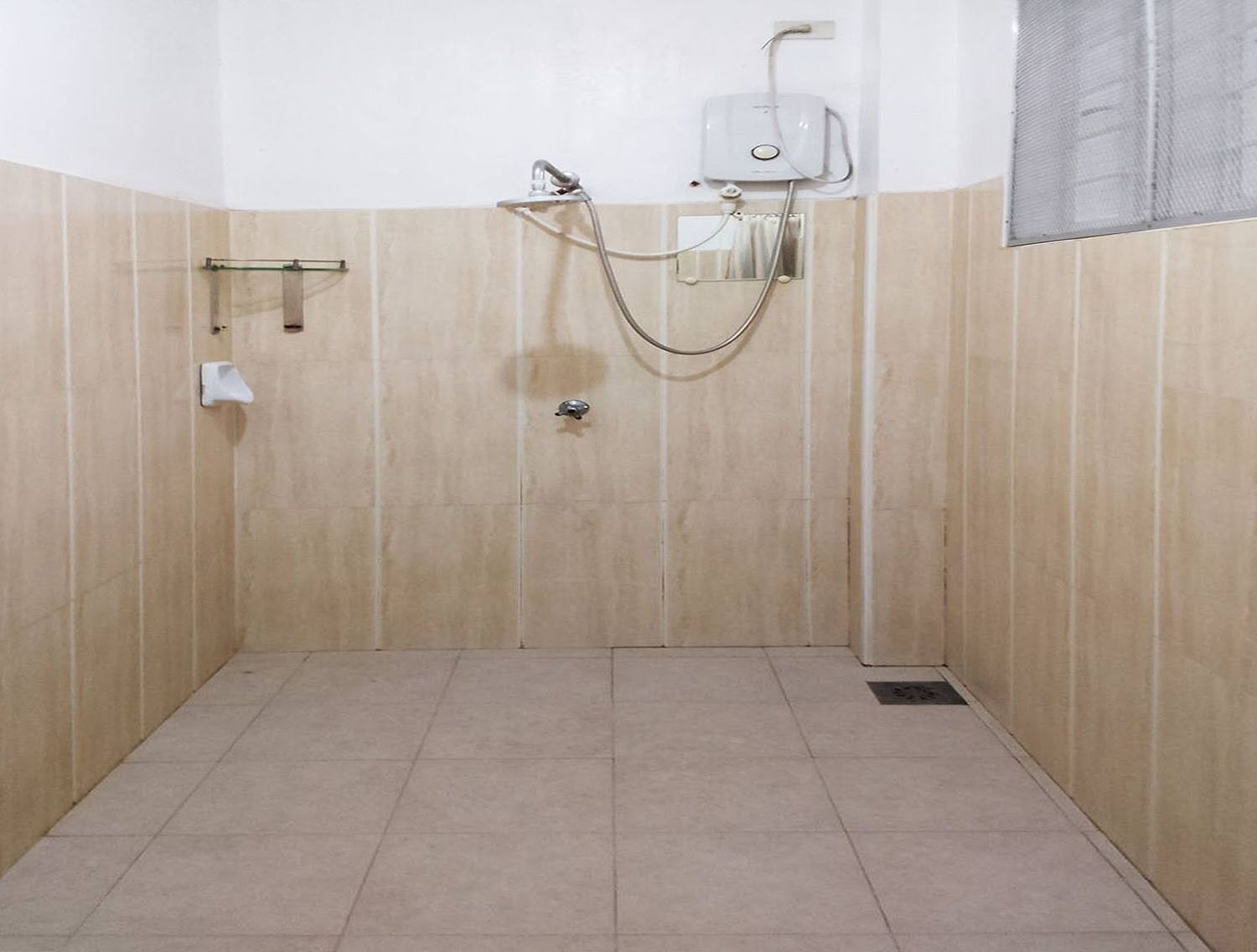 Un pequeño baño revestido de azulejos con un solo grifo y un cabezal de ducha de mano.