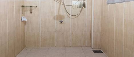 Un pequeño baño revestido de azulejos con un solo grifo y un cabezal de ducha de mano.