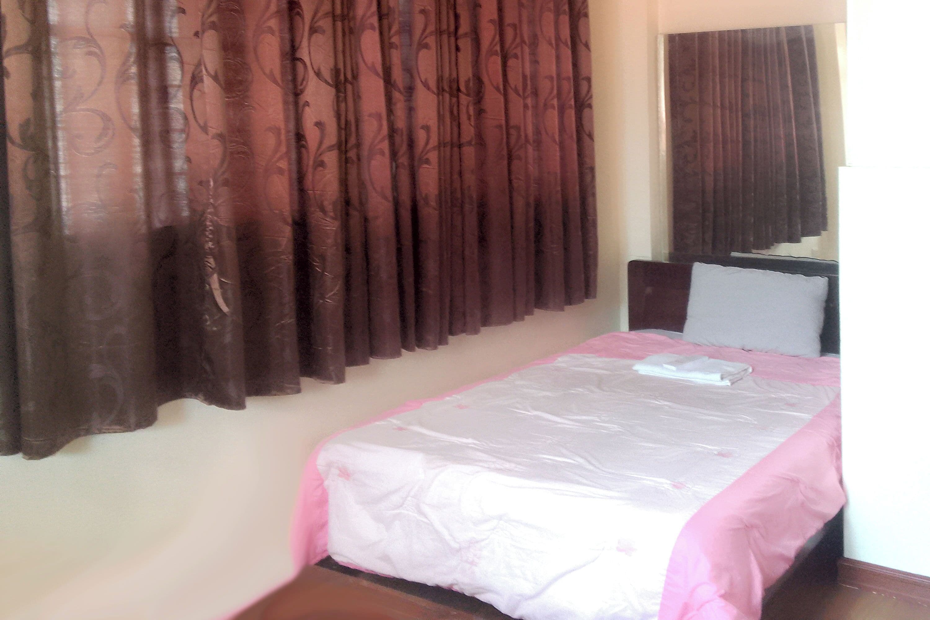 A bedroom with a bed, a headboard, and curtains.