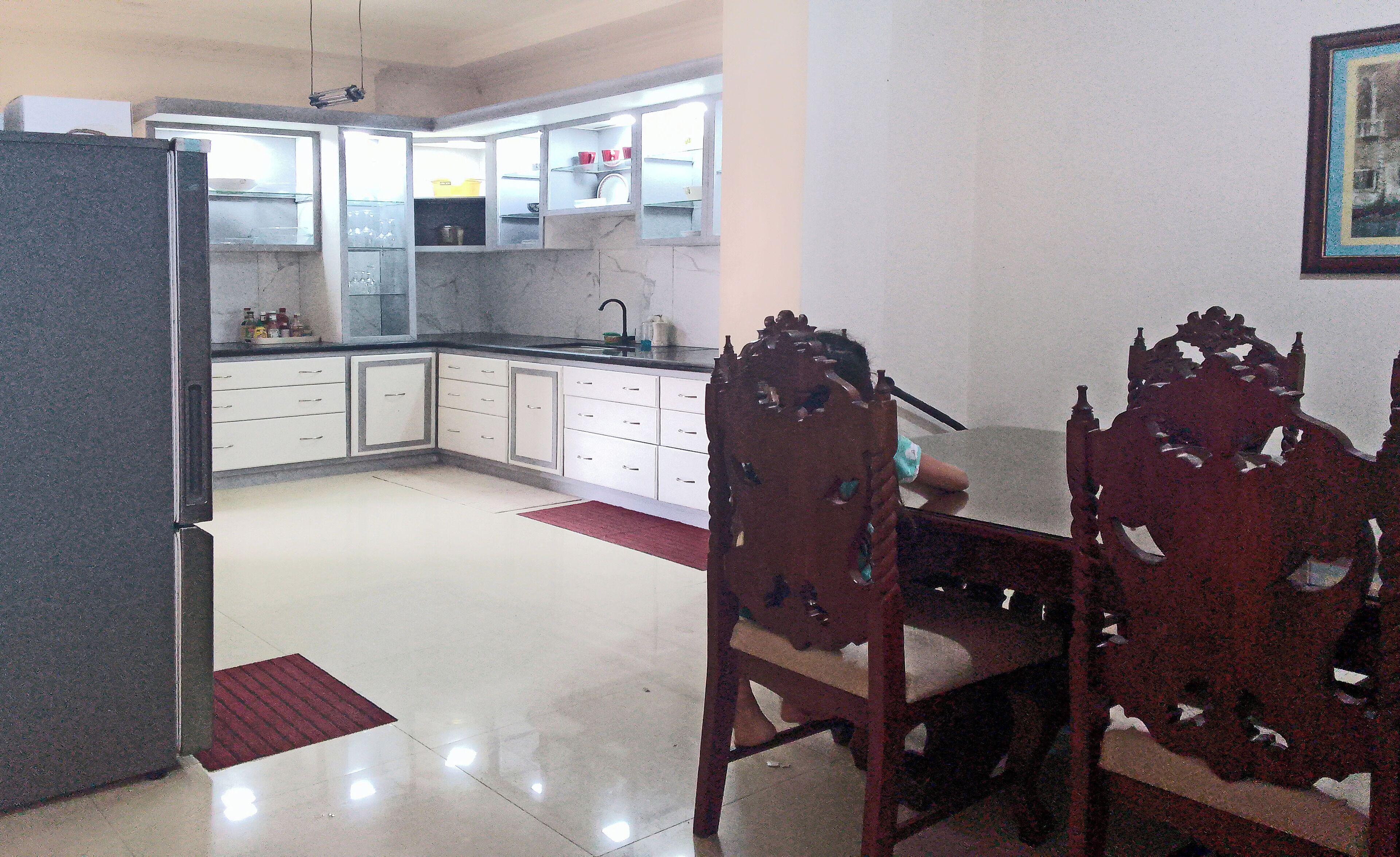 Una cocina con armarios blancos, una mesa de comedor con sillas y una alfombra roja.