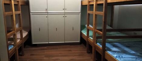 Una habitación con literas, un armario y suelo de madera.
