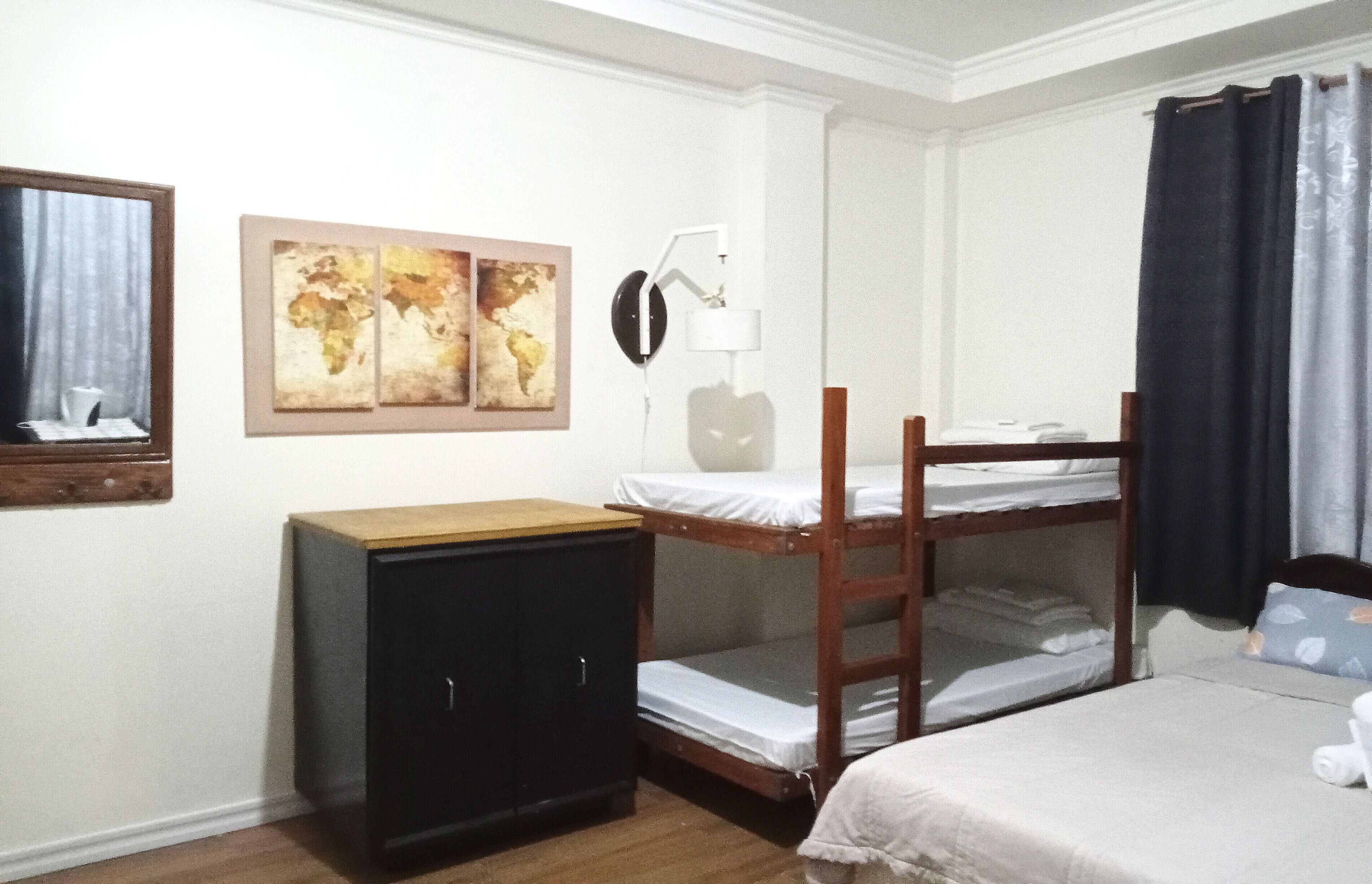 A bedroom with bunk beds, a desk, a lamp, and artwork on the wall.