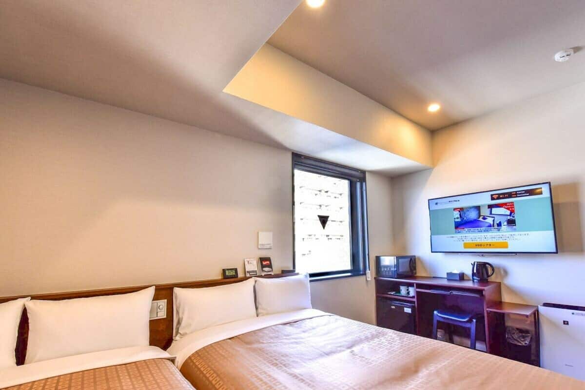 Ett hotellrum med en stor säng, ett skrivbord, en tv och ett fönster.