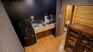 A compact kitchen with a refrigerator, sink, and wooden cabinets. - Kyokoi Reishikamogawa (Kyoto)