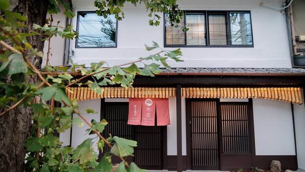 A traditional Japanese building with a white exterior, dark wooden doors, and a decorative bamboo awning. - Kyokoi Reishikamogawa (Kyoto)
