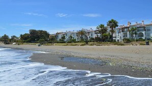 Een hotel aan het strand met meerlaags gebouwen, palmbomen en een zandstrand.