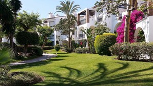 Um jardim bem cuidado, com gramados aparados, arbustos variados e plantas floridas.