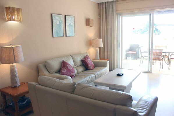 A living room with a beige sofa, two pillows, a coffee table, and two wall-mounted lamps. - Front beach location between Estepona and Marbella (Estepona)