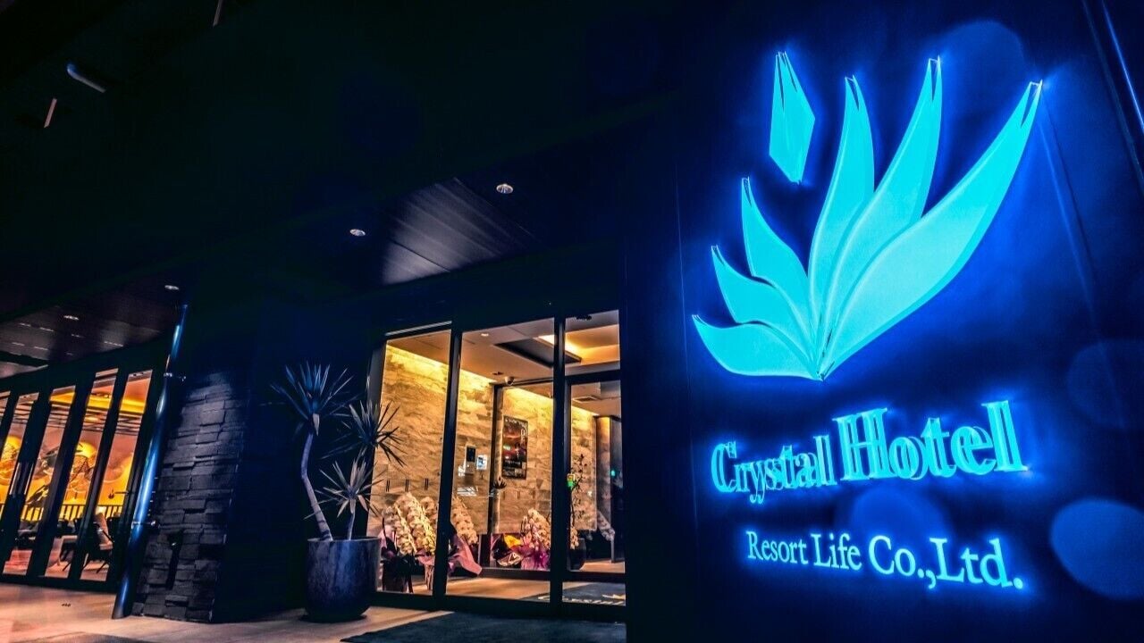 The exterior of Crystal Hotel with a prominent illuminated logo and entrance.