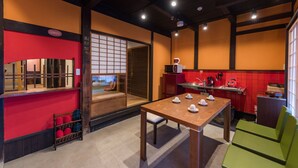 A modern kitchen with a wooden table, red and yellow walls, and a traditional sliding door. - Kyokoi Kiyomizusaryou (Kyoto)