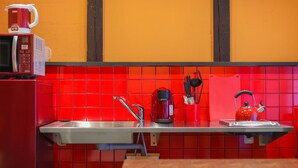 A kitchen with red tiles, a microwave, a coffee maker, a kettle, and a sink. - Kyokoi Kiyomizusaryou (Kyoto)