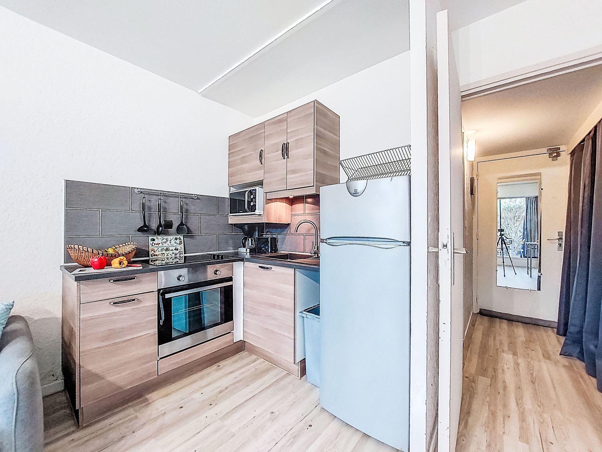 A compact kitchen with wooden cabinets, a microwave, an oven, and a refrigerator.